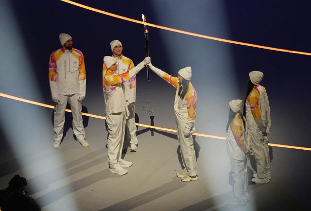 (260207) -- MILAN, Feb. 7, 2026 (Xinhua) -- Torchbearers pass the flame during the opening ceremony of the Milan-Cortina 2026 Olympic Winter Games at the San Siro Olympic Stadium in Milan, Italy, Feb. 6, 2026. (Xinhua/Cheng Min)