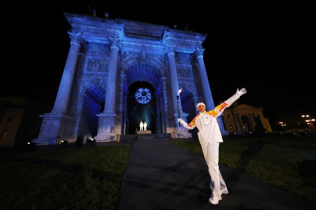 (260207) -- MILAN, Feb. 7, 2026 (Xinhua) -- Torchbearers Enrico Fabris passes the Olympic flame during the opening ceremony of the Milan-Cortina 2026 Olympic Winter Games at the Arco della Pace in Milan, Italy, Feb. 6, 2026. (Jamie Squire/Pool via Xinhua)