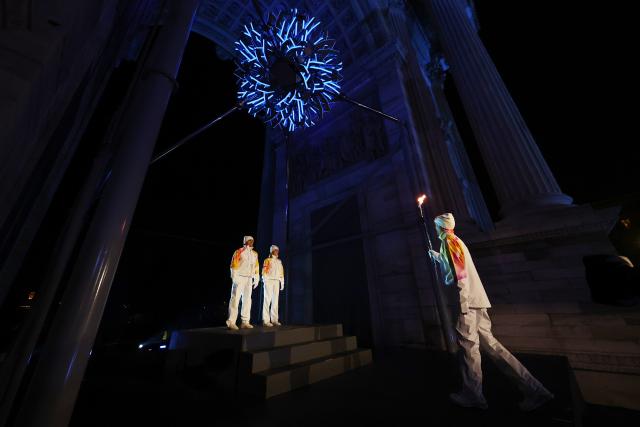 (260207) -- MILAN, Feb. 7, 2026 (Xinhua) -- Torchbearers Enrico Fabris (R) passes the Olympic flame to Deborah Compagnoni (C) and Alberto Tomba during the opening ceremony of the Milan-Cortina 2026 Olympic Winter Games at the Arco della Pace in Milan, Italy, Feb. 6, 2026. (Jamie Squire/Pool via Xinhua)
