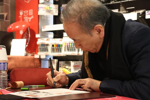 (260207) -- PARIS, Feb. 7, 2026 (Xinhua) -- Chen Jianghong, an artist of Chinese origin, also the designer of the stamps, signs on the Year of the Horse commemorative stamps during a launching ceremony in Paris, France, Feb. 6, 2026. France's La Poste Group on Friday issued two stamps to celebrate the upcoming Chinese Lunar New Year, the Year of the Horse. (Xinhua/Zhang Baihui)