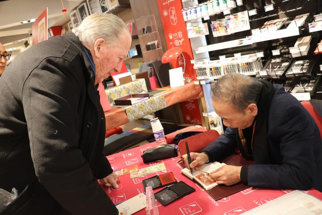 (260207) -- PARIS, Feb. 7, 2026 (Xinhua) -- Chen Jianghong (R), an artist of Chinese origin, also the designer of the stamps, signs on the Year of the Horse commemorative stamps during a launching ceremony in Paris, France, Feb. 6, 2026. France's La Poste Group on Friday issued two stamps to celebrate the upcoming Chinese Lunar New Year, the Year of the Horse. (Xinhua/Zhang Baihui)