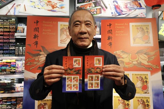 (260207) -- PARIS, Feb. 7, 2026 (Xinhua) -- Chen Jianghong, an artist of Chinese origin, also the designer of the stamps, displays the Year of the Horse commemorative stamps during a launching ceremony in Paris, France, Feb. 6, 2026. France's La Poste Group on Friday issued two stamps to celebrate the upcoming Chinese Lunar New Year, the Year of the Horse. (Xinhua/Zhang Baihui)