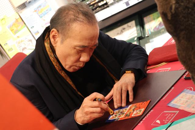 (260207) -- PARIS, Feb. 7, 2026 (Xinhua) -- Chen Jianghong, an artist of Chinese origin, also the designer of the stamps, signs on the Year of the Horse commemorative stamps during a launching ceremony in Paris, France, Feb. 6, 2026. France's La Poste Group on Friday issued two stamps to celebrate the upcoming Chinese Lunar New Year, the Year of the Horse. (Xinhua/Zhang Baihui)