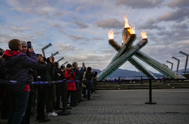 (260207) -- VANCOUVER, Feb. 7, 2026 (Xinhua) -- People gather by the Olympic Cauldron at Jack Poole Plaza in Vancouver, British Columbia, Canada, Feb. 6, 2026. The Olympic Cauldron in Vancouver was relit on Friday to mark the opening day of the 2026 Milan-Cortina Winter Olympics in Italy. (Photo by Liang Sen/Xinhua)