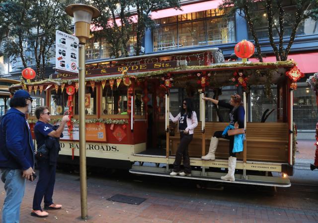 (260207) -- SAN FRANCISCO, Feb. 7, 2026 (Xinhua) -- Women pose for a photo with a sightseeing cable car decorated to celebrate the upcoming Chinese New Year in San Francisco, the United States, Feb. 6, 2026. (Photo by Liu Yilin/Xinhua)