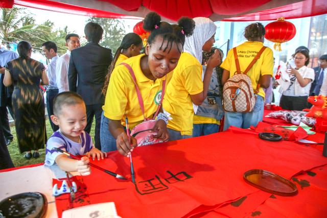 (260207) -- DAR ES SALAAM, Feb. 7, 2026 (Xinhua) -- A Tanzanian guest and a Chinese child experience Chinese calligraphy in Dar es Salaam, Tanzania, Feb. 6, 2026. Tanzanians on Friday evening joined overseas Chinese to celebrate the upcoming Spring Festival, also known as the Chinese New Year, at the Chinese Embassy in Tanzania.
   TO GO WITH "Tanzanians, overseas Chinese celebrate upcoming Spring Festival in Dar es Salaam" (Xinhua/Emmanuel Herman)
