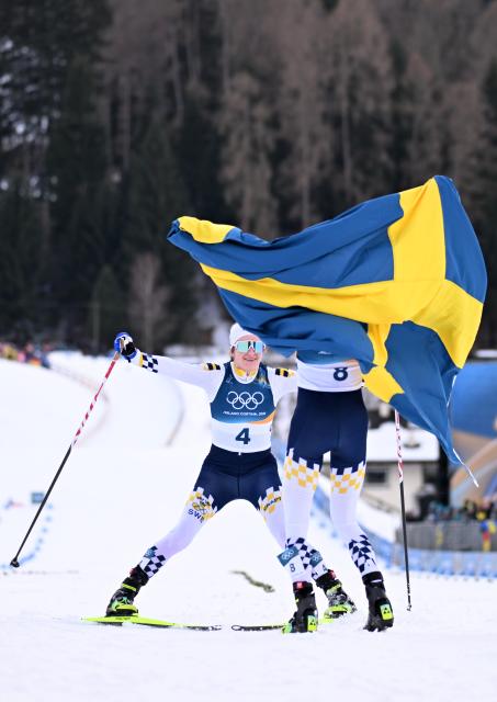 (260207) -- TESERO, Feb. 7, 2026 (Xinhua) -- Frida Karlsson (R) of Sweden and her teammate Ebba Andersson celebrate after the Cross-Country Skiing Women's 10km+10km Skiathlon of the Milan-Cortina 2026 Olympic Winter Games in Tesero, Italy, Feb. 7, 2026. (Xinhua/He Canling)