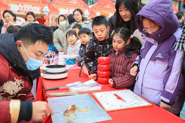 (260208) -- BEIJING, Feb. 8, 2026 (Xinhua) -- Children observe the creation of a Chinese sugar painting in Nanjing, east China's Jiangsu Province, Feb. 7, 2026.
  As the Spring Festival approaches, various activities featuring time-honored traditions are held across the country, filling the air with great excitement. (Photo by Su Yang/Xinhua)