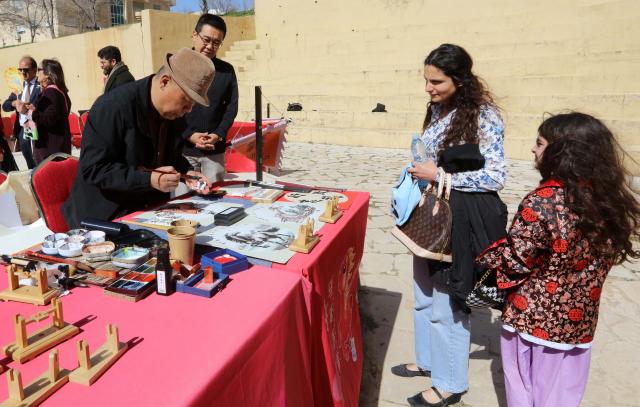 (260208) -- AMMAN, Feb. 8, 2026 (Xinhua) -- Jordanians watch a Chinese artist painting at a Chinese cultural and tourism fair in Amman, Jordan, Feb. 7, 2026. (Photo by Mohammad Abu Ghosh/Xinhua)