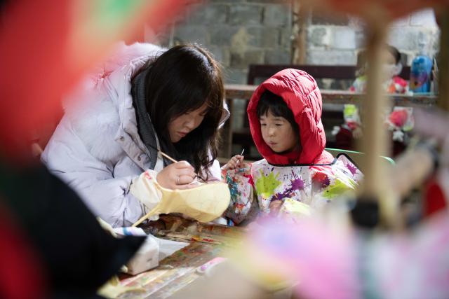 (260208) -- YIXIAN, Feb. 8, 2026 (Xinhua) -- A woman and her child make a fish lantern in Bishan Village of Yixian County, east China's Anhui Province, Feb. 7, 2026.
  Ancient villages in Yixian County are filled with festive vibe as the Spring Festival approaches. Locals follow folk customs by making steamed rice cakes, fish lanterns, and writing spring couplets, drawing tourists to share the festive joy together. (Xinhua/Zhang Duan)
