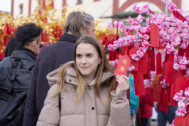 (260208) -- BUDAPEST, Feb. 8, 2026 (Xinhua) -- A woman poses for photos with a card written in Chinese characters meaning well-being during the Budapest Chinatown Spring Festival Temple Fair in Budapest, Hungary, on Feb. 7, 2026. TO GO WITH "Feature: Budapest embraces Chinese Spring Festival as cultural bridge between civilizations" (Photo by Attila Volgyi/Xinhua)
