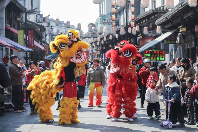 (260208) -- JIANDE, Feb. 8, 2026 (Xinhua) -- Tourists watch Lion dance performances at Shouchang ancient town in Jiande, east China's Zhejiang Province, Feb. 8, 2026. Shouchang ancient town has recently held traditional folk activities such as folk parades, dragon and lion dances, and a lantern show to welcome the Chinese New Year. (Xinhua/Xu Yu)