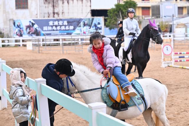 (260208) -- XIAPU, Feb. 8, 2026 (Xinhua) -- A girl learns horse riding at a racecourse of a cultural and creative base in Xiapu County, southeast China's Fujian Province, Feb. 7, 2026. Horse-themed tourism has surged recently in Xiapu County as the lunar Year of the Horse approaches. (Xinhua/Jiang Kehong)