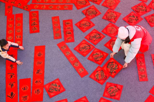 (260208) -- BEIJING, Feb. 8, 2026 (Xinhua) -- A student volunteer (R) sorts calligraphy works at Hai'an, east China's Jiangsu Province, on Feb. 8, 2026. Various extracurricular activities are available for students across China during the winter vacation. (Photo by Gu Binbin/Xinhua)