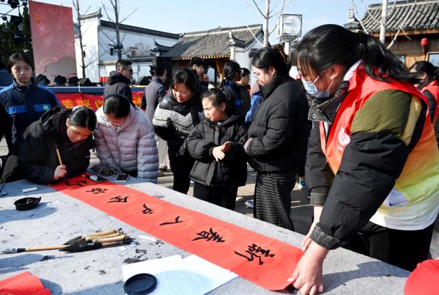 (260208) -- BEIJING, Feb. 8, 2026 (Xinhua) -- Students write spring couplets for charity sale in Wuyi County of Jinhua, east China's Zhejiang Province, on Feb. 8, 2026. Various extracurricular activities are available for students across China during the winter vacation. (Photo by Zhang Jiancheng/Xinhua)