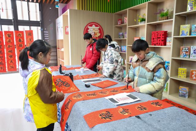 (260208) -- BEIJING, Feb. 8, 2026 (Xinhua) -- Students write spring couplets in an event celebrating the upcoming Spring Festival at a bookstore in Xinghua City, east China's Jiangsu Province, on Feb. 7, 2026. Various extracurricular activities are available for students across China during the winter vacation. (Photo by Zhou Shegen/Xinhua)