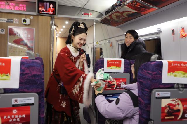 (260209) -- LANZHOU, Feb. 9, 2026 (Xinhua) -- A museum staff member presents cultural and creative products to a passenger aboard the train G848 in northwest China's Gansu Province, Feb. 9, 2026. As part of the mobile museum on the high-speed railway program, the train G848, carrying cultural relics interpreters, departed from Lanzhou West Railway Station heading to Guangzhou South Railway Station on Monday.
   Nine of China's national first-grade museums in Gansu, including the Dunhuang Academy and Gansu Provincial Museum, have brought the cultural heritage of Gansu onto the train, allowing passengers to touch history and get to know traditional custom during the Spring Festival travel rush. (Xinhua/Zhang Zhimin)