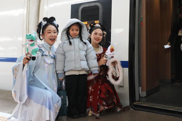 (260209) -- LANZHOU, Feb. 9, 2026 (Xinhua) -- Museum staff members pose for a photo with a girl at Lanzhou West Railway Station in Lanzhou, northwest China's Gansu Province, Feb. 9, 2026. As part of the mobile museum on the high-speed railway program, the train G848, carrying cultural relics interpreters, departed from Lanzhou West Railway Station heading to Guangzhou South Railway Station on Monday.
   Nine of China's national first-grade museums in Gansu, including the Dunhuang Academy and Gansu Provincial Museum, have brought the cultural heritage of Gansu onto the train, allowing passengers to touch history and get to know traditional custom during the Spring Festival travel rush. (Xinhua/Zhang Zhimin)