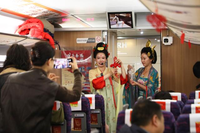 (260209) -- LANZHOU, Feb. 9, 2026 (Xinhua) -- Museum staff members introduce cultural knowledge to passengers aboard the train G848 in northwest China's Gansu Province, Feb. 9, 2026. As part of the mobile museum on the high-speed railway program, the train G848, carrying cultural relics interpreters, departed from Lanzhou West Railway Station heading to Guangzhou South Railway Station on Monday.
   Nine of China's national first-grade museums in Gansu, including the Dunhuang Academy and Gansu Provincial Museum, have brought the cultural heritage of Gansu onto the train, allowing passengers to touch history and get to know traditional custom during the Spring Festival travel rush. (Xinhua/Zhang Zhimin)