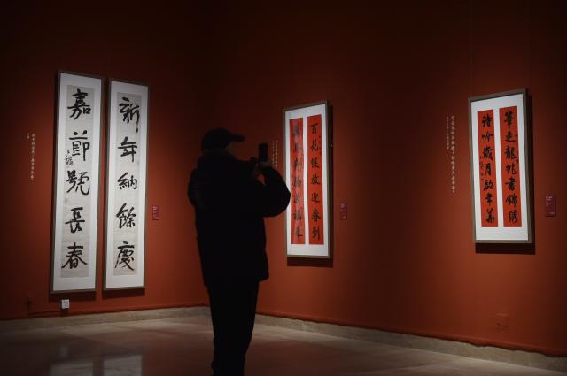 (260209) -- BEIJING, Feb. 9, 2026 (Xinhua) -- A visitor takes a photo of calligraphy works at the National Art Museum of China in Beijing, capital of China, Feb. 9, 2026. The opening ceremony of the Spring Festival Exhibition Series of National Art Museum of China (NAMOC) was held here on Monday. The series includes five exhibitions, covering various art forms such as Chinese painting, oil painting, printmaking, sculpture, etc. (Xinhua/Lu Peng)