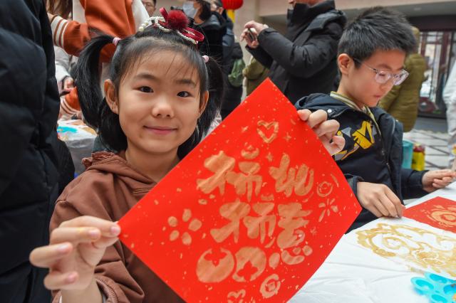 (260210) -- BEIJING, Feb. 10, 2026 (Xinhua) -- A child displays a Spring Festival decoration at the Changchun Library in Changchun, northeast China's Jilin Province, Feb. 10, 2026. Various kinds of activities were held on Tuesday to celebrate the traditional Chinese Xiaonian Festival in northern China, which marks the start of the countdown to the Spring Festival. (Xinhua/Zhang Nan)
