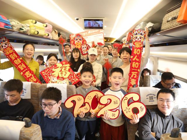 (260210) -- BEIJING, Feb. 10, 2026 (Xinhua) -- Passengers and train attendants pose for a group photo on train No. G415 travelling from Jinan, east China's Shandong Province, to Guangzhou, south China's Guangdong Province, on Feb. 10, 2026. Various kinds of activities were held on Tuesday to celebrate the traditional Chinese Xiaonian Festival in northern China, which marks the start of the countdown to the Spring Festival. (Photo by Jiang Aiyong/Xinhua)