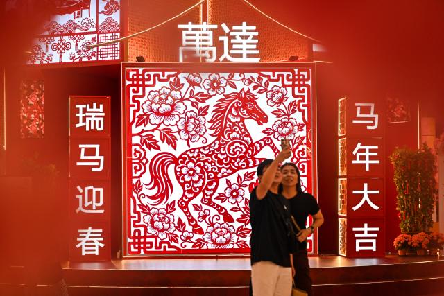 (260210) -- KUALA LUMPUR, Feb. 10, 2026 (Xinhua) -- People take a selfie in front of a horse decoration for the upcoming Chinese New Year at a mall in Kuala Lumpur, Malaysia, Jan. 30, 2026. As the Spring Festival approaches, traditional Chinese art of paper-cutting featuring the Year of the Horse increased the festive atmosphere in Malaysia. (Photo by Chong Voon Chung/Xinhua)