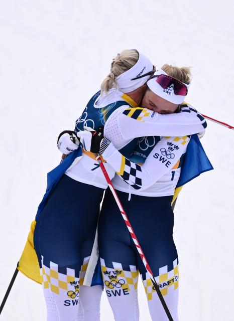 (260210) -- TESERO, Feb. 10, 2026 (Xinhua) -- Gold medalist Linn Svahn (R) of Sweden and bronze medalist Maja Dahlqvist of Sweden hug each other after the cross-country skiing women's sprint classic final at the Milan-Cortina 2026 Olympic Winter Games in Tesero, Italy, Feb. 10, 2026. (Xinhua/He Canling)