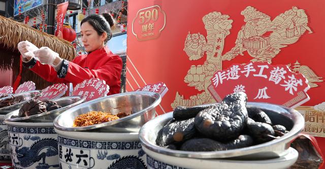 (260210) -- BEIJING, Feb. 10, 2026 (Xinhua) -- A merchant packs pickles for customers at a Spring Festival market of Longfusi commercial area in Dongcheng District of Beijing, capital of China, on Feb. 10, 2026. As the Spring Festival approaches, the Longfusi commercial area is filled with festive atmosphere, attracting a large number of citizens and tourists to visit here. (Xinhua/Chang Nengjia)