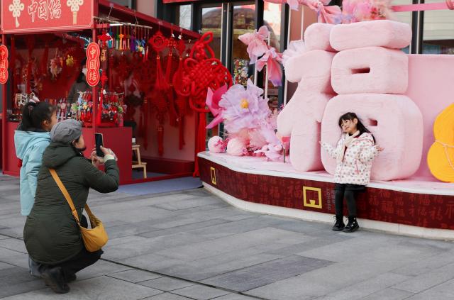 (260210) -- BEIJING, Feb. 10, 2026 (Xinhua) -- A girl poses for photos at a Spring Festival market of Longfusi commercial area in Dongcheng District of Beijing, capital of China, on Feb. 10, 2026. As the Spring Festival approaches, the Longfusi commercial area is filled with festive atmosphere, attracting a large number of citizens and tourists to visit here. (Xinhua/Chang Nengjia)