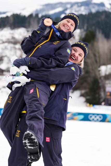 (260210) -- TESERO, Feb. 10, 2026 (Xinhua) -- Gold medalist Linn Svahn (R) of Sweden lifts bronze medalist Maja Dahlqvist of Sweden to celebrate after the cross-country skiing women's sprint classic final at the Milano Cortina 2026 Olympic Winter Games in Tesero, Italy, Feb. 10, 2026. (Xinhua/Peng Ziyang)