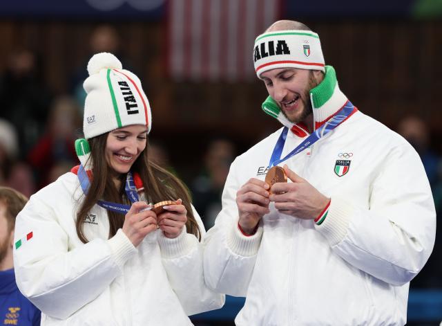 (260210) -- CORTINA D'AMPEZZO, Feb. 10, 2026 (Xinhua) -- Stefania Constantini (L) and Amos Mosaner of Italy look at their medals during the awarding ceremony of the curling mixed doubles at the Milan-Cortina 2026 Olympic Winter Games in Cortina, Italy, Feb. 10, 2026. (Xinhua/Ding Xu)