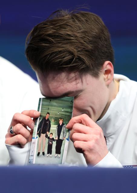 (260210) -- MILAN, Feb. 10, 2026 (Xinhua) -- Maxim Naumov of the United States shows a photo of his parents who were killed in a plane crash last year, after the short program competition of figure skating men single skating at the Milan-Cortina 2026 Olympic Winter Games in Milan, Italy, Feb. 10, 2026. (Xinhua/Li Ming)