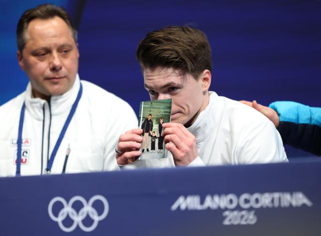 (260210) -- MILAN, Feb. 10, 2026 (Xinhua) -- Maxim Naumov (R) of the United States shows a photo of his parents who were killed in a plane crash last year, after the short program competition of figure skating men single skating at the Milan-Cortina 2026 Olympic Winter Games in Milan, Italy, Feb. 10, 2026. (Xinhua/Li Ming)