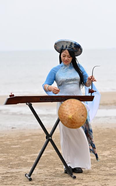 (260211) -- DONGXING, Feb. 11, 2026 (Xinhua) -- Su Haizhen plays the Duxianqin on Jintan Beach in Dongxing City, south China's Guangxi Zhuang Autonomous Region, Feb. 7, 2026. On Jintan Beach in Dongxing City of south China's Guangxi Zhuang Autonomous Region, Su Haizhen plays the Duxianqin, or single-stringed musical instrument, showcasing the unique charm of the Jing ethnic group's special instrument.
   The Jing people are among China's smaller ethnic minority groups, and the only one whose economy is primarily based on marine fishing. They mainly reside in Dongxing City of Guangxi. Duxianqin is a distinctive ethnic instrument of Dongxing's Jing community. With just one string and one lever, it can produce six registers and three octaves. In 2011, the Duxianqin art of Jing people was listed as one of the national intangible cultural heritages in China. 
   Su Haizhen, a Jing native from Dongxing who grew up by the sea, comes from a family that has been dedicated to preserving Jing culture since her grandfather's generation. In 1987, she began formally studying to play the Duxianqin. Today, she is a regional-level representative inheritor of the Duxianqin art of Jing people in the autonomous region. Over nearly four decades of research, inheriting, and development of the instrument, Su has been continuously refining her playing skills while improving the instrument's craftsmanship and exploring innovative performance styles. She is also committed to nurturing more enthusiasts and inheritors of the art.
   In 2023, after becoming a member of the National Committee of the Chinese People's Political Consultative Conference, Su Haizhen felt a stronger sense of mission and responsibility to preserve and promote China's traditional culture. While advocating for Duxianqin education in schools, she has been exploring ways to further highlight the cultural appeal of the art. Leveraging Dongxing's geographical proximity to Vietnam, she aims to foster deeper cultural exchanges and cooperation between China and ASEAN countries like Vietnam. (Xinhua/Lu Boan)