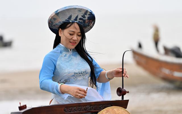 (260211) -- DONGXING, Feb. 11, 2026 (Xinhua) -- Su Haizhen plays the Duxianqin on Jintan Beach in Dongxing City, south China's Guangxi Zhuang Autonomous Region, Feb. 7, 2026. On Jintan Beach in Dongxing City of south China's Guangxi Zhuang Autonomous Region, Su Haizhen plays the Duxianqin, or single-stringed musical instrument, showcasing the unique charm of the Jing ethnic group's special instrument.
   The Jing people are among China's smaller ethnic minority groups, and the only one whose economy is primarily based on marine fishing. They mainly reside in Dongxing City of Guangxi. Duxianqin is a distinctive ethnic instrument of Dongxing's Jing community. With just one string and one lever, it can produce six registers and three octaves. In 2011, the Duxianqin art of Jing people was listed as one of the national intangible cultural heritages in China. 
   Su Haizhen, a Jing native from Dongxing who grew up by the sea, comes from a family that has been dedicated to preserving Jing culture since her grandfather's generation. In 1987, she began formally studying to play the Duxianqin. Today, she is a regional-level representative inheritor of the Duxianqin art of Jing people in the autonomous region. Over nearly four decades of research, inheriting, and development of the instrument, Su has been continuously refining her playing skills while improving the instrument's craftsmanship and exploring innovative performance styles. She is also committed to nurturing more enthusiasts and inheritors of the art.
   In 2023, after becoming a member of the National Committee of the Chinese People's Political Consultative Conference, Su Haizhen felt a stronger sense of mission and responsibility to preserve and promote China's traditional culture. While advocating for Duxianqin education in schools, she has been exploring ways to further highlight the cultural appeal of the art. Leveraging Dongxing's geographical proximity to Vietnam, she aims to foster deeper cultural exchanges and cooperation between China and ASEAN countries like Vietnam. (Xinhua/Lu Boan)