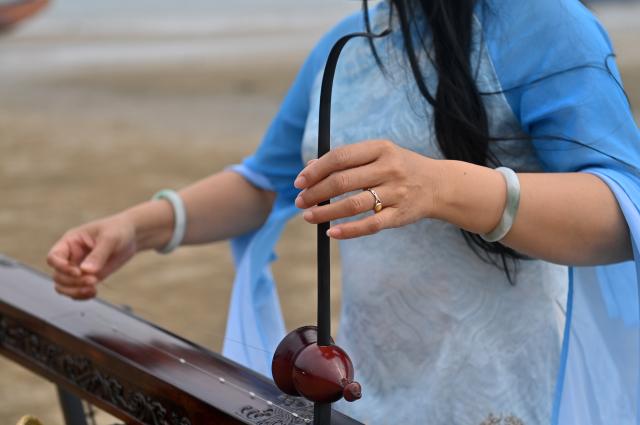 (260211) -- DONGXING, Feb. 11, 2026 (Xinhua) -- Su Haizhen plays the Duxianqin on Jintan Beach in Dongxing City, south China's Guangxi Zhuang Autonomous Region, Feb. 7, 2026. On Jintan Beach in Dongxing City of south China's Guangxi Zhuang Autonomous Region, Su Haizhen plays the Duxianqin, or single-stringed musical instrument, showcasing the unique charm of the Jing ethnic group's special instrument.
   The Jing people are among China's smaller ethnic minority groups, and the only one whose economy is primarily based on marine fishing. They mainly reside in Dongxing City of Guangxi. Duxianqin is a distinctive ethnic instrument of Dongxing's Jing community. With just one string and one lever, it can produce six registers and three octaves. In 2011, the Duxianqin art of Jing people was listed as one of the national intangible cultural heritages in China. 
   Su Haizhen, a Jing native from Dongxing who grew up by the sea, comes from a family that has been dedicated to preserving Jing culture since her grandfather's generation. In 1987, she began formally studying to play the Duxianqin. Today, she is a regional-level representative inheritor of the Duxianqin art of Jing people in the autonomous region. Over nearly four decades of research, inheriting, and development of the instrument, Su has been continuously refining her playing skills while improving the instrument's craftsmanship and exploring innovative performance styles. She is also committed to nurturing more enthusiasts and inheritors of the art.
   In 2023, after becoming a member of the National Committee of the Chinese People's Political Consultative Conference, Su Haizhen felt a stronger sense of mission and responsibility to preserve and promote China's traditional culture. While advocating for Duxianqin education in schools, she has been exploring ways to further highlight the cultural appeal of the art. Leveraging Dongxing's geographical proximity to Vietnam, she aims to foster deeper cultural exchanges and cooperation between China and ASEAN countries like Vietnam. (Xinhua/Lu Boan)