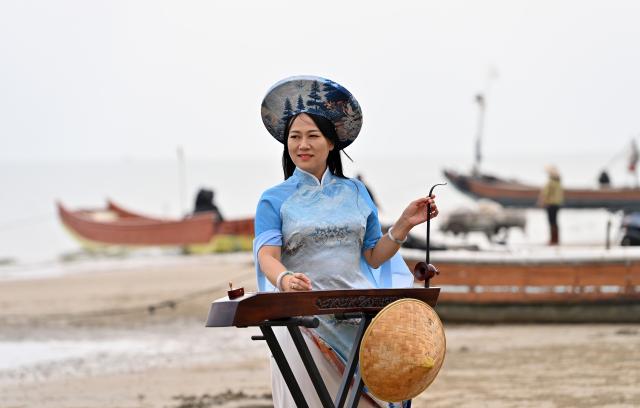 (260211) -- DONGXING, Feb. 11, 2026 (Xinhua) -- Su Haizhen looks out to the sea while playing the Duxianqin on Jintan Beach in Dongxing City, south China's Guangxi Zhuang Autonomous Region, Feb. 7, 2026. On Jintan Beach in Dongxing City of south China's Guangxi Zhuang Autonomous Region, Su Haizhen plays the Duxianqin, or single-stringed musical instrument, showcasing the unique charm of the Jing ethnic group's special instrument.
   The Jing people are among China's smaller ethnic minority groups, and the only one whose economy is primarily based on marine fishing. They mainly reside in Dongxing City of Guangxi. Duxianqin is a distinctive ethnic instrument of Dongxing's Jing community. With just one string and one lever, it can produce six registers and three octaves. In 2011, the Duxianqin art of Jing people was listed as one of the national intangible cultural heritages in China. 
   Su Haizhen, a Jing native from Dongxing who grew up by the sea, comes from a family that has been dedicated to preserving Jing culture since her grandfather's generation. In 1987, she began formally studying to play the Duxianqin. Today, she is a regional-level representative inheritor of the Duxianqin art of Jing people in the autonomous region. Over nearly four decades of research, inheriting, and development of the instrument, Su has been continuously refining her playing skills while improving the instrument's craftsmanship and exploring innovative performance styles. She is also committed to nurturing more enthusiasts and inheritors of the art.
   In 2023, after becoming a member of the National Committee of the Chinese People's Political Consultative Conference, Su Haizhen felt a stronger sense of mission and responsibility to preserve and promote China's traditional culture. While advocating for Duxianqin education in schools, she has been exploring ways to further highlight the cultural appeal of the art. Leveraging Dongxing's geographical proximity to Vietnam, she aims to foster deeper cultural exchanges and cooperation between China and ASEAN countries like Vietnam. (Xinhua/Lu Boan)