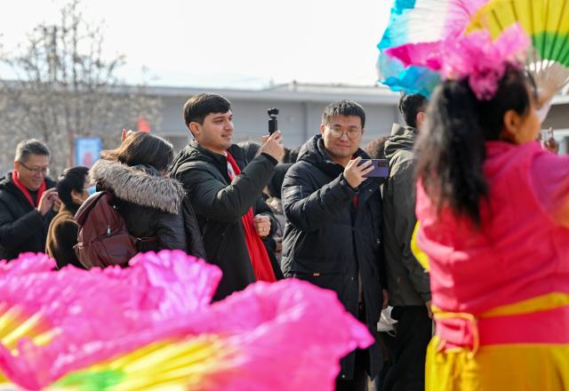 (260211) -- TIANJIN, Feb. 11, 2026 (Xinhua) -- Suleimanov Umar (4th L) films a video in Chuanfangyu Town of Jizhou District, north China's Tianjin, Feb. 10, 2026. On the occasion of traditional Chinese Xiaonian Festival in northern China, which fell on Tuesday this year, Suleimanov Umar, a 26-year-old Tajikistan student in Nankai University of Tianjin, and other international students visited a local festive fair in Chuanfangyu Town to experience the vibrant traditions of Chinese New Year. Celebrated on the 23rd day of the last month of the Chinese lunar calendar, Xiaonian is a festival marking the start of the countdown to the Chinese New Year.
   When Suleimanov was a child, most neighbors were Chinese working in Tajikistan, thus he was deeply impressed by Chinese New Year traditions such as putting up Spring Festival couplets and making dumplings.
   When in middle school, he began studying Chinese at local Confucius Institute, and then chose to go to university in China with the support of his family. While staying in China he immersed himself in social practice and actively participated in cultural exchange activities.
    Speaking of the future, Suleimanov said, "I hope I could engage in diplomatic work after graduation and strive to become an envoy of friendship". (Xinhua/Zhao Zishuo)