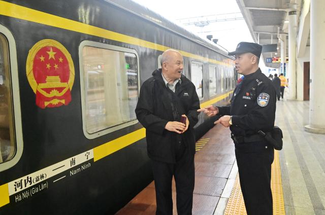 (260211) -- NANNING, Feb. 11, 2026 (Xinhua) -- Huang Qingming talks with a passenger at a platform of the Nanning Railway Station in Nanning, south China's Guangxi Zhuang Autonomous Region, Feb. 10, 2026. The China-Vietnam international passenger rail service, which resumed operations on May 25, 2025, is now facing its first Spring Festival travel rush. Huang Qingming, a 58-year-old railway police officer, has been working on this route since 2012, responsible for the Nanning-Pingxiang section of trains No. T8701 and No. T8702 in Guangxi. 
   As a railway police officer, handling various emergencies, conducting train's security check and ensuring passenger safety during the journey are part of Huang's daily routine.
   Approaching retirement, Huang cherishes his role deeply, "Serving as a railway police officer on the China-Vietnam international passenger rail service, safeguarding the trains' security and passengers' safety, has been an honorable and unforgettable experience in my career." (Xinhua/Lu Boan)