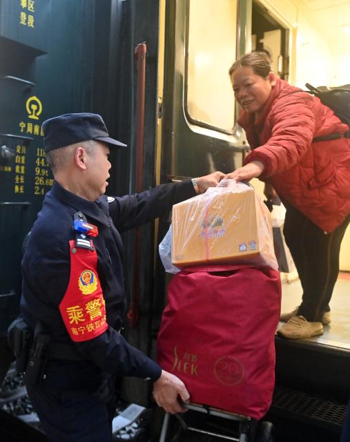 (260211) -- NANNING, Feb. 11, 2026 (Xinhua) -- Huang Qingming helps a passenger with her belongings at the Chongzuo Railway Station in Chongzuo, south China's Guangxi Zhuang Autonomous Region, Feb. 11, 2026. The China-Vietnam international passenger rail service, which resumed operations on May 25, 2025, is now facing its first Spring Festival travel rush. Huang Qingming, a 58-year-old railway police officer, has been working on this route since 2012, responsible for the Nanning-Pingxiang section of trains No. T8701 and No. T8702 in Guangxi. 
   As a railway police officer, handling various emergencies, conducting train's security check and ensuring passenger safety during the journey are part of Huang's daily routine.
   Approaching retirement, Huang cherishes his role deeply, "Serving as a railway police officer on the China-Vietnam international passenger rail service, safeguarding the trains' security and passengers' safety, has been an honorable and unforgettable experience in my career." (Xinhua/Lu Boan)