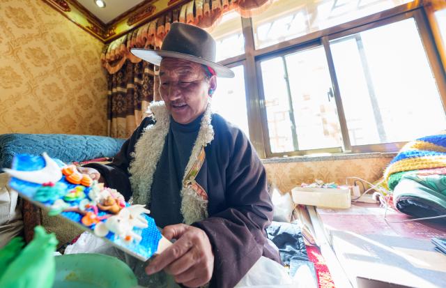 (260212) -- LHASA, Feb. 12, 2026 (Xinhua) -- A craftsman makes a butter sculpture at a workshop in Lhasa, southwest China's Xizang Autonomous Region, Feb. 12, 2026. Butter sculptures in vivid shapes of trees, flowers, birds, stars, etc., are gradually gaining popularity in the markets across the city ahead of the Tibetan New Year.
   These sculptures, made skillfully with colored butter, convey people's good wishes for the New Year. (Xinhua/Tenzin Nyida)