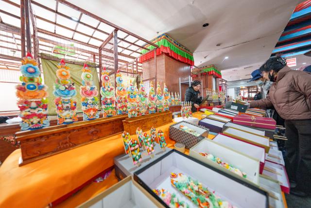 (260212) -- LHASA, Feb. 12, 2026 (Xinhua) -- People shop for butter sculptures at a stall in a local market in Lhasa, southwest China's Xizang Autonomous Region, Feb. 12, 2026. Butter sculptures in vivid shapes of trees, flowers, birds, stars, etc., are gradually gaining popularity in the markets across the city ahead of the Tibetan New Year.
   These sculptures, made skillfully with colored butter, convey people's good wishes for the New Year. (Xinhua/Tenzin Nyida)