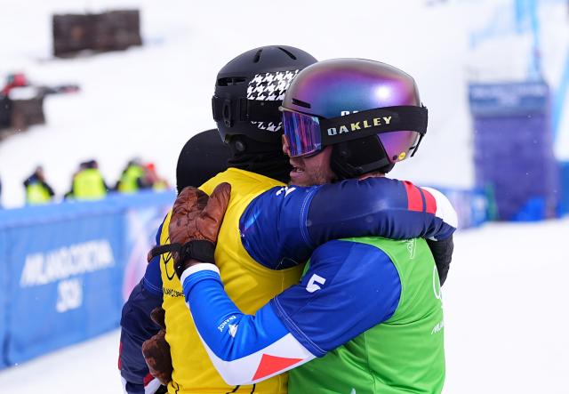 (260212) -- LIVIGNO, Feb. 12, 2026 (Xinhua) -- Nick Baumgartner (L) of the United States hugs with Loan Bozzolo of France after the snowboard men's cross small final at the Milan-Cortina 2026 Olympic Winter Games in Livigno, Italy, Feb. 12, 2026. (Xinhua/Wu Huiwo)