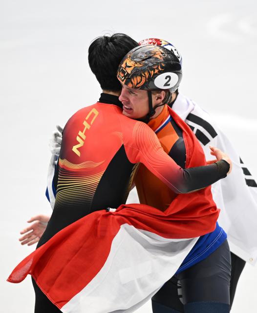 (260212) -- MILAN, Feb. 12, 2026 (Xinhua) -- Sun Long (L) of China hugs Jens van 'T Wout of the Netherlands after the short track speed skating men's 1000m final A at the Milan-Cortina 2026 Olympic Winter Games in Milan, Italy, Feb. 12, 2026. (Xinhua/Cheng Min)