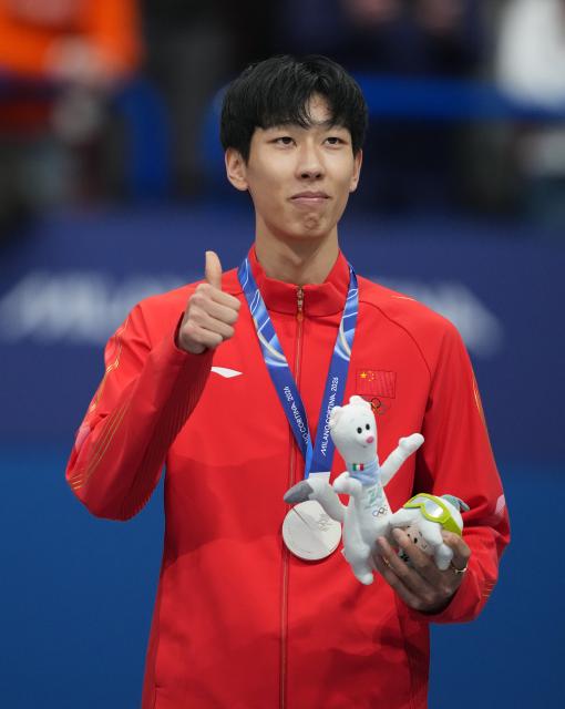 (260212) -- MILAN, Feb. 12, 2026 (Xinhua) -- Silver medalist Sun Long of China thumbs up during the awarding ceremony of the short track speed skating men's 1000m at the Milan-Cortina 2026 Olympic Winter Games in Milan, Italy, Feb. 12, 2026. (Xinhua/Xue Yuge)