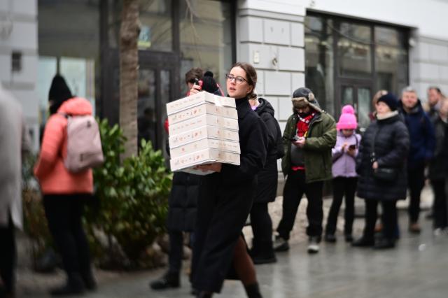 (260212) -- WARSAW, Feb. 12, 2026 (Xinhua) -- A woman carries six boxes of traditional doughnuts on a street in Warsaw, Poland on Feb. 12, 2026. People in Poland eat traditional doughnuts on Fat Thursday to mark the last Thursday before the start of Lent. (Photo by Aleksy Witwicki/Xinhua)