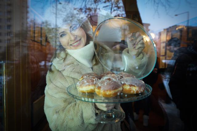 (260212) -- WARSAW, Feb. 12, 2026 (Xinhua) -- A woman displays traditional doughnuts in a shop window in Warsaw, Poland on Feb. 12, 2026. People in Poland eat traditional doughnuts on Fat Thursday to mark the last Thursday before the start of Lent. (Photo by Jaap Arriens/Xinhua)