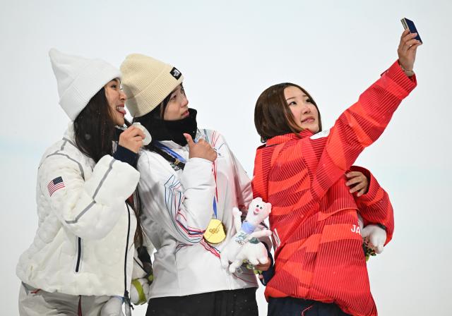 (260213) -- LIVIGNO, Feb. 13, 2026 (Xinhua) -- Gold medalist Choi Gaon (C) of South Korea, silver medalist Chloe Kim (L) of the United States and bronze medalist Ono Mitsuki of Japan take selfies on the podium after the women's snowboard halfpipe final at the Milan-Cortina 2026 Olympic Winter Games in Livigno, Italy, Feb. 12, 2026. (Xinhua/Zhang Hongxiang)