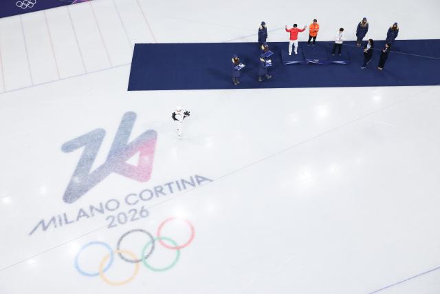 (260213) -- MILAN, Feb. 13, 2026 (Xinhua) -- Silver medalist Sun Long (red) of China reacts during the awarding ceremony of the short track speed skating men's 1000m at the Milan-Cortina 2026 Olympic Winter Games in Milan, Italy, Feb. 12, 2026. (Xinhua/Chen Yichen)